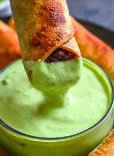 Plate of baked black bean taquitos with fresh toppings.