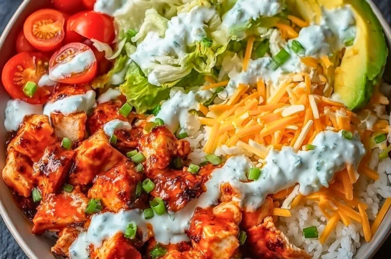 A vibrant bowl featuring Buffalo Chicken with fresh vegetables and rice.