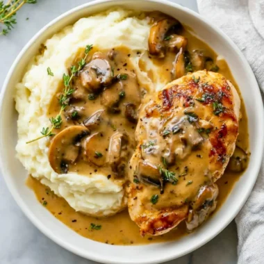 Creamy mushroom chicken dish served on a plate garnished with herbs.