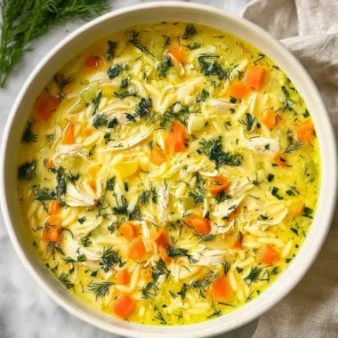 Bowl of Greek Lemon Chicken Soup garnished with fresh herbs and lemon slices.