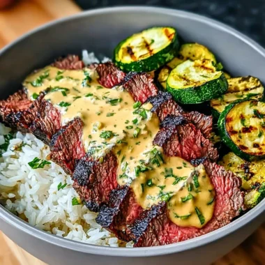 Grilled steak bowl with sauce and sliced grilled zucchini served in a bowl