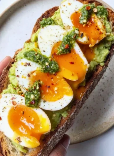 Delicious pesto avocado toast topped with eggs, perfect for brunch.