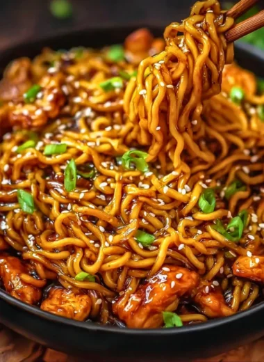 Delicious Sticky Garlic Chicken Noodles served in a bowl, garnished with herbs.