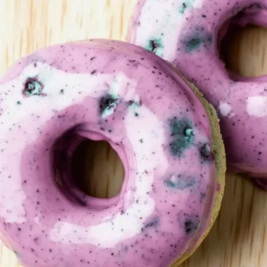 Freshly baked blueberry cake donuts topped with a blueberry glaze.