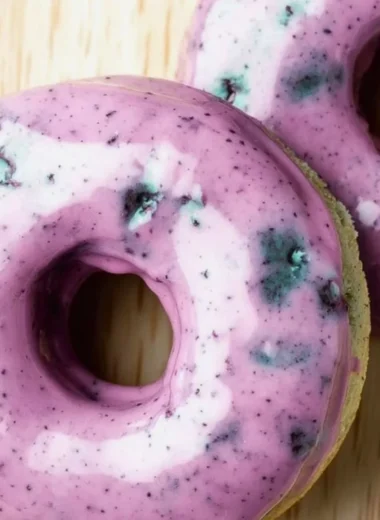 Freshly baked blueberry cake donuts topped with a blueberry glaze.