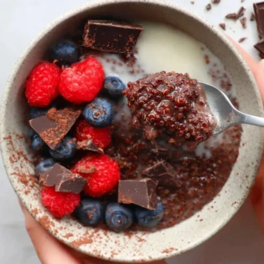 Dark chocolate quinoa breakfast bowl topped with fruits and nuts