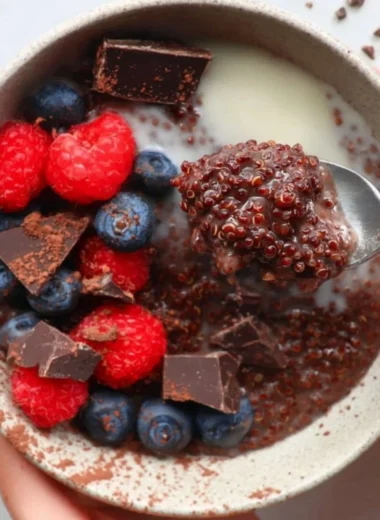 Dark chocolate quinoa breakfast bowl topped with fruits and nuts