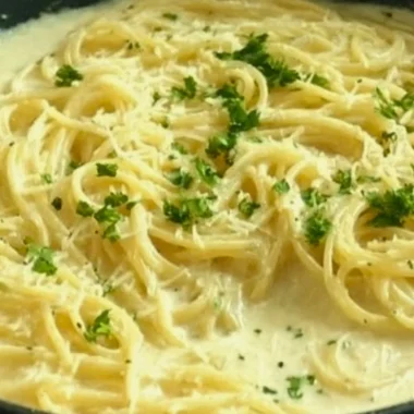 Creamy Garlic Parmesan Sauce drizzled over pasta in a white dish