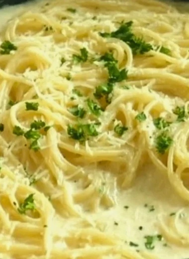 Creamy Garlic Parmesan Sauce drizzled over pasta in a white dish