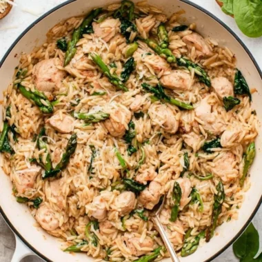 High protein chicken orzo served in a bowl with fresh herbs and vegetables