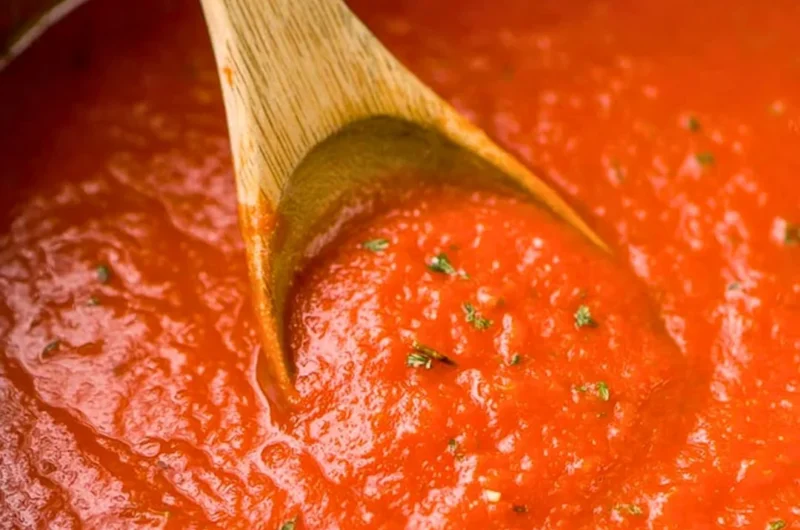 A bowl of homemade marinara sauce with fresh tomatoes and herbs