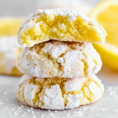 Freshly baked lemon crinkle cookies dusted with powdered sugar on a plate.