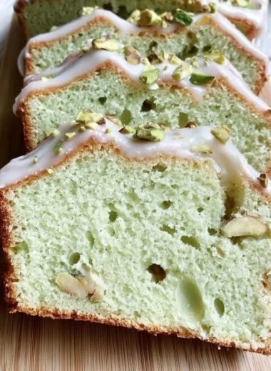Slice of moist pistachio pudding bread with nuts on a wooden table
