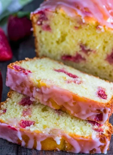 Slice of moist strawberry pound cake topped with fresh strawberries and whipped cream