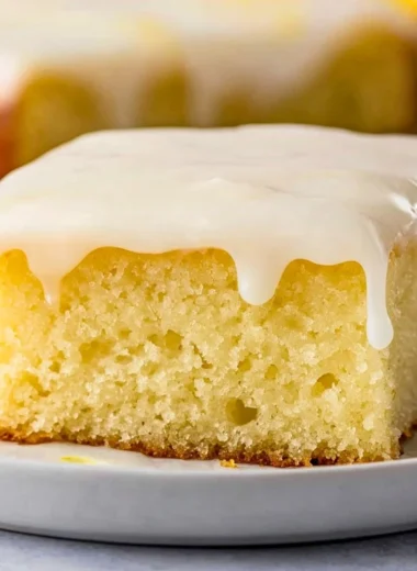 Cozy Lemonade Poke Cake topped with fresh lemon slices and whipped cream