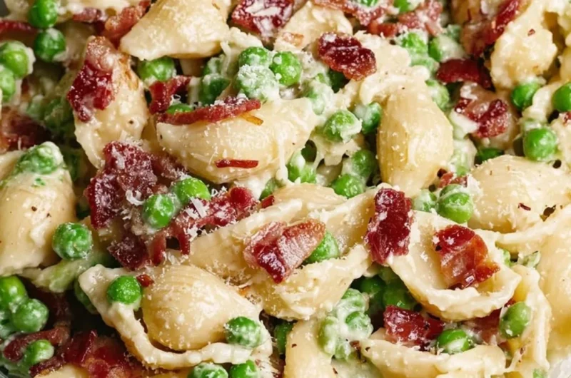 Creamy pea and bacon pasta salad served in a bowl, garnished with fresh herbs.