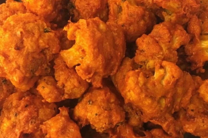 Crispy baked buffalo cauliflower wings served on a plate with dipping sauce.