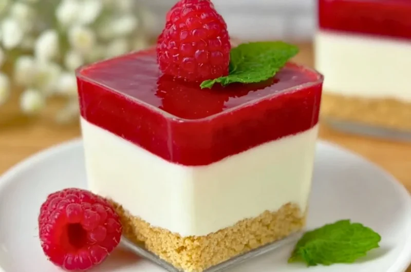 Raspberry cheesecake served in a glass with fresh raspberries and cream
