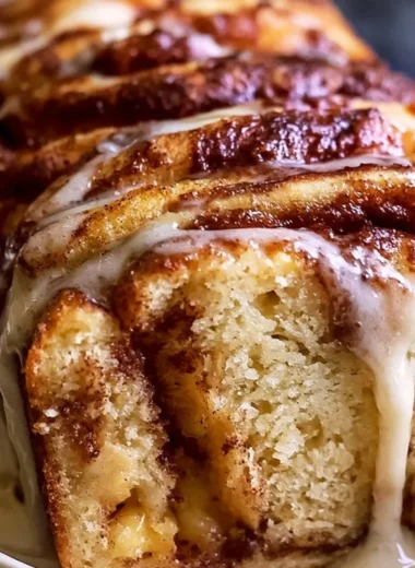 A freshly baked apple cinnamon swirl bread on a wooden cutting board.