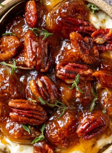 Baked feta dip topped with fig jam and pecans served in a dish